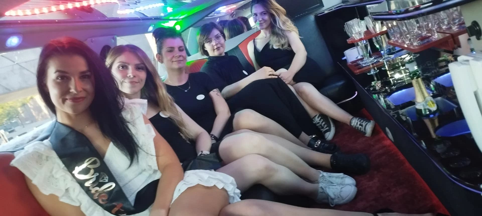 Grupa kobiet świętuje wieczór panieński we wnętrzu elegancko podświetlonej limuzyny.