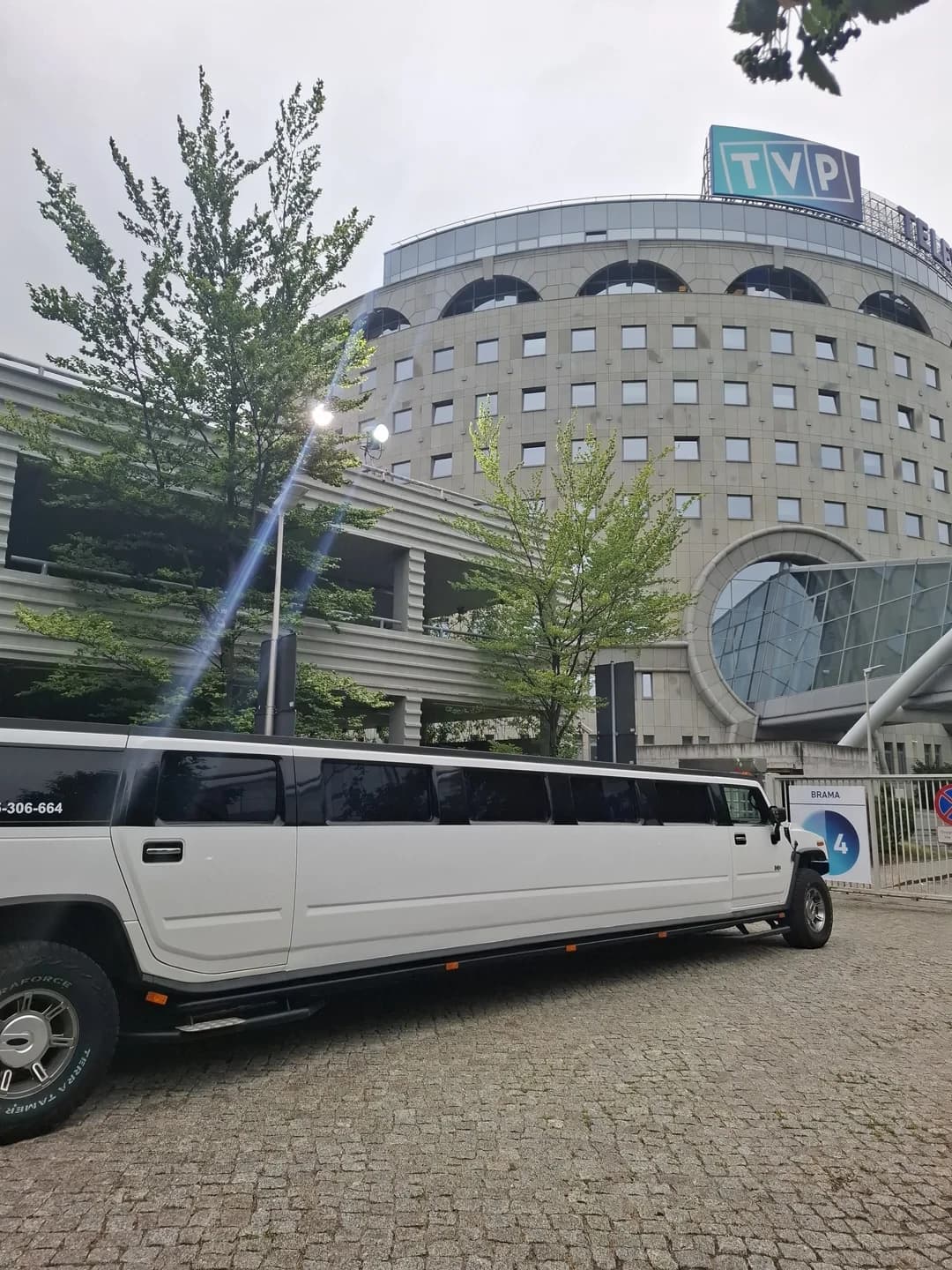 Długa, biała limuzyna Hummer zaparkowana przed siedzibą TVP w Warszawie.